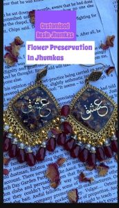 "Handcrafted resin earrings with maroon and golden design, featuring real dried flower preservation and elegant calligraphy in the center.